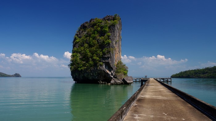 Limestone rock formation in the sea with a pier in Thailand