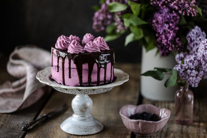 Pink cake with chocolate drizzle and lilac flowers