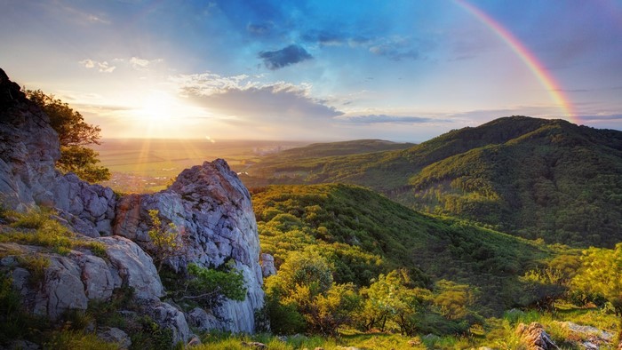 Mountain landscape with rainbow and sun rays