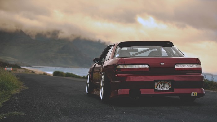 Red Nissan Silvia S13 parked on a coastal road