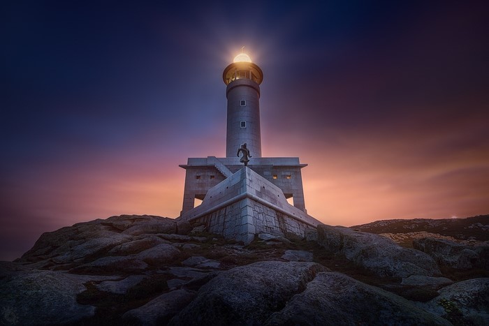 Lighthouse on a rocky coast at sunset