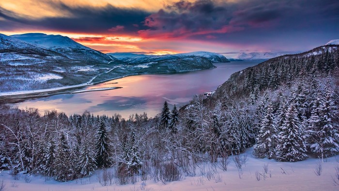 Snowy mountain landscape with a fjord at dawn