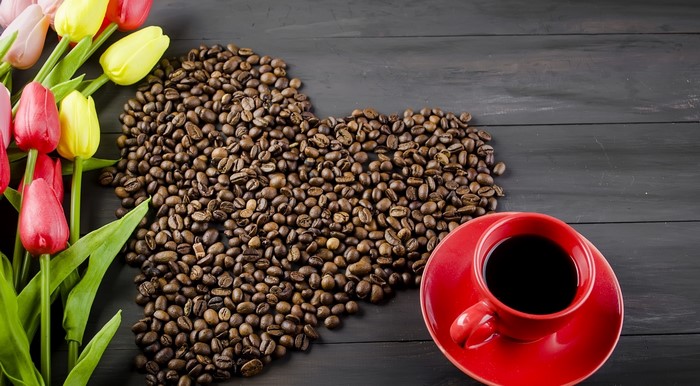 Coffee beans in heart shape with tulips and coffee cup