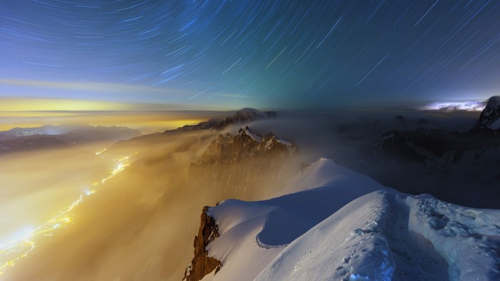 Star trails over Aiguille du Midi valley with city lights