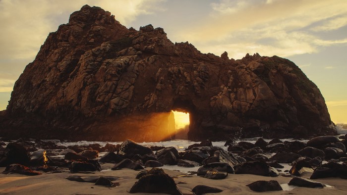 Sunset through rock arch at Pfeiffer Beach, Big Sur, California
