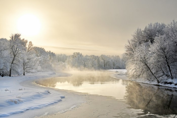 Winter river with frost-covered trees and sun