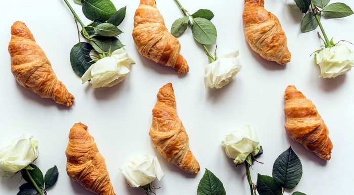 Croissants and white roses on a white background