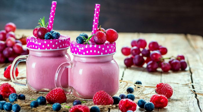 Pink berry smoothies in mason jars with fresh fruits