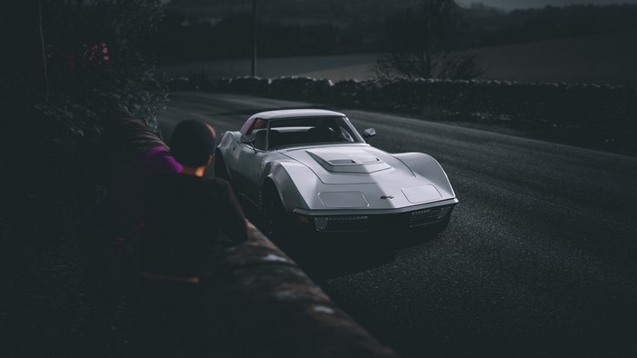 Silver Chevrolet Corvette C3 on a dark road