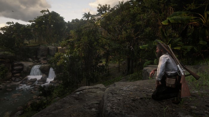 Man with rifle in jungle near waterfall in Red Dead Redemption 2