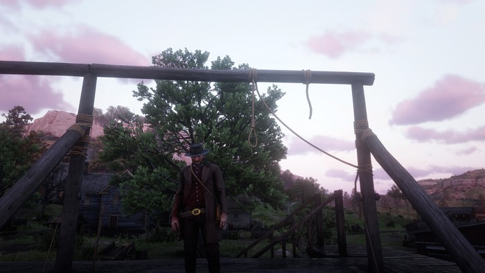 Man in Western attire stands near a gallows in Red Dead Redemption 2