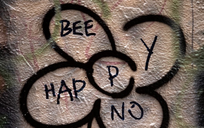Graffiti with text "BEE HAPPY" on a wall