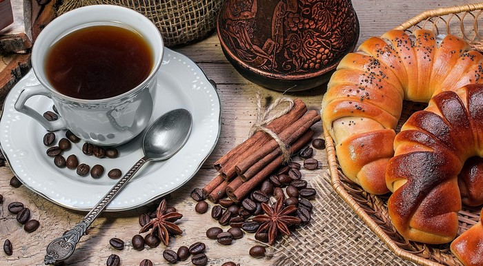 Coffee cup with pastries, cinnamon sticks, and coffee beans