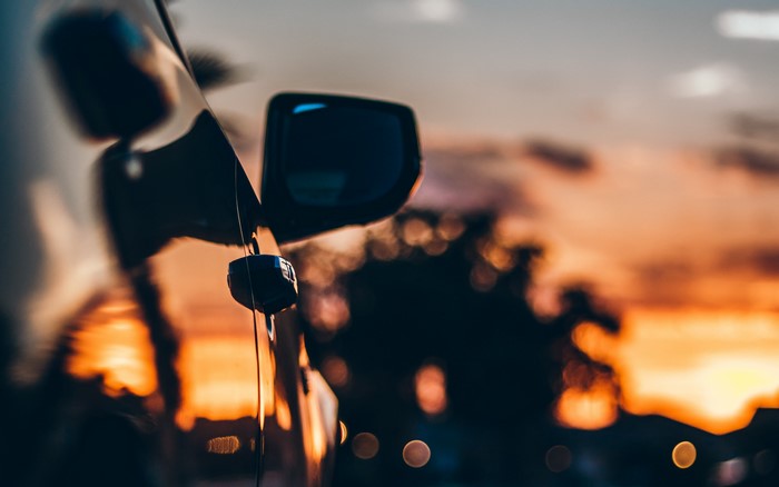 Car mirror reflecting sunset with bokeh