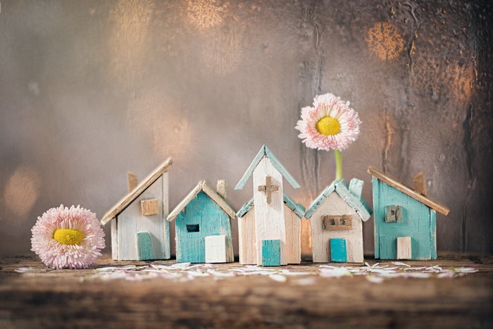 Miniature houses and flowers on a wooden surface