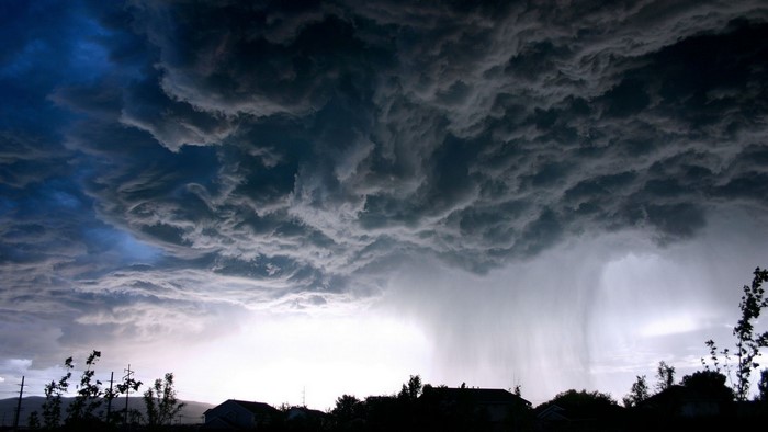 Storm clouds with rain over houses and trees