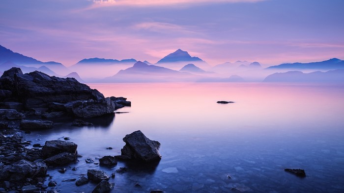 Misty mountains over a calm lake at dawn
