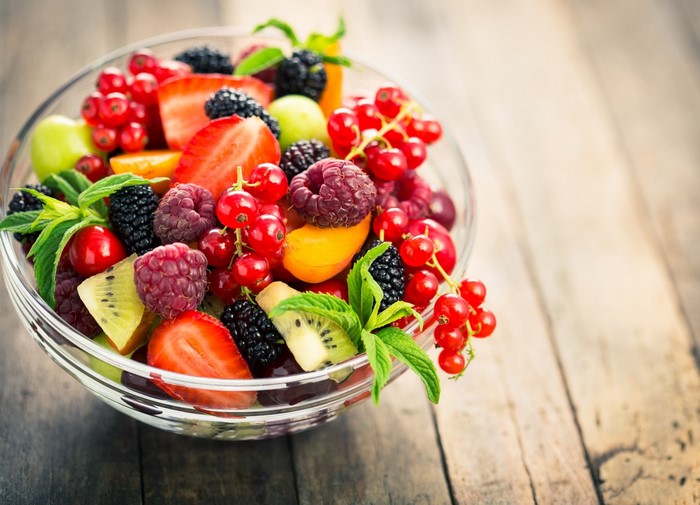 Bowl of fresh berries and fruit on a wooden surface
