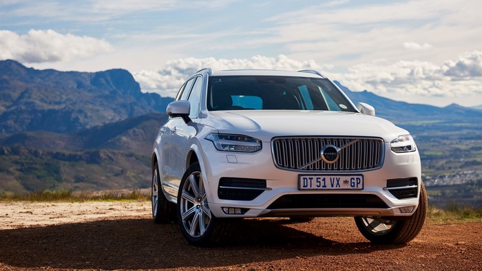 White Volvo XC90 SUV parked on a dirt road with mountains