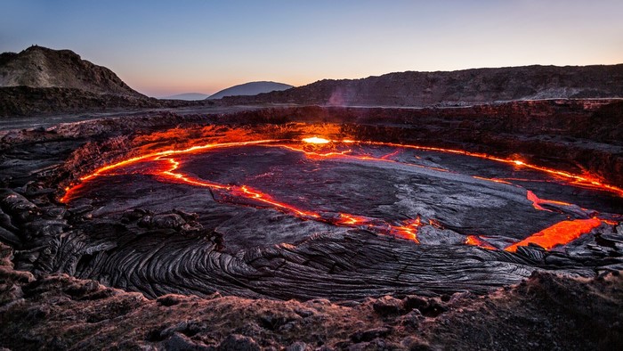 Lava lake in a volcanic landscape at dusk