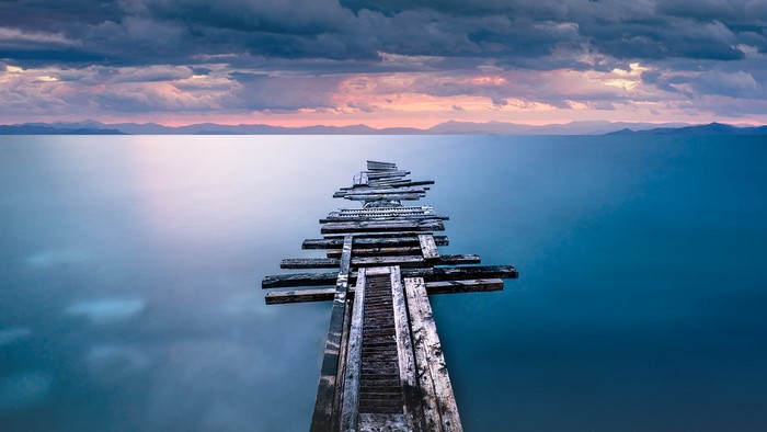 Wooden pier over calm water at sunset