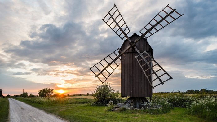 Wooden windmill at sunset with a dirt road