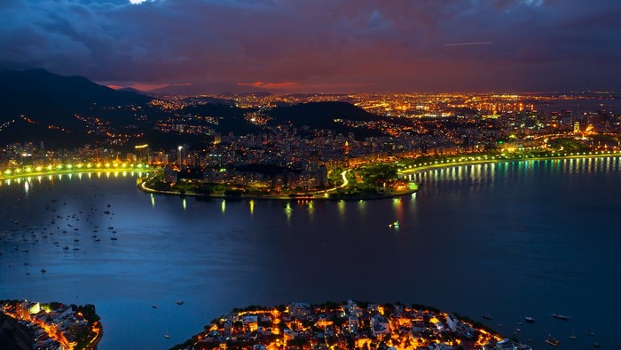 Aerial view of Rio de Janeiro cityscape at night with mountains and coast