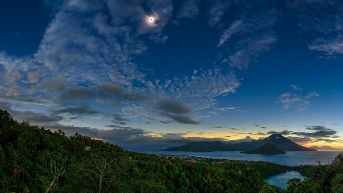 Solar eclipse over islands and mountains at sunset