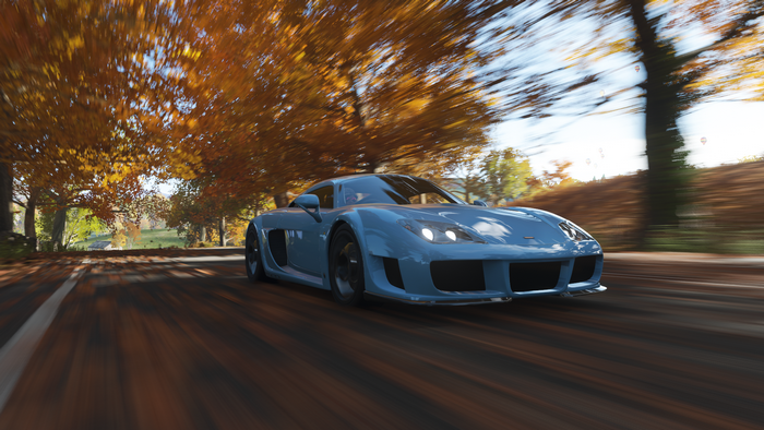 Blue sports car driving on a road in autumn