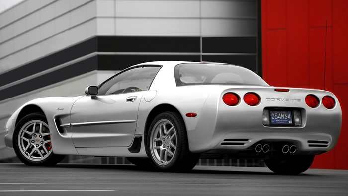 Silver Chevrolet Corvette C5 parked in front of a modern building