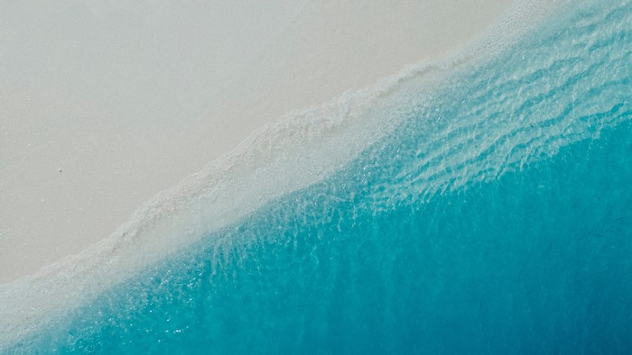 Turquoise sea waves washing onto a white sand beach