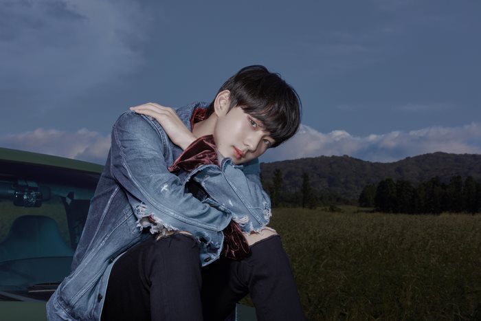 Jungwon ENHYPEN sitting on a car in a field