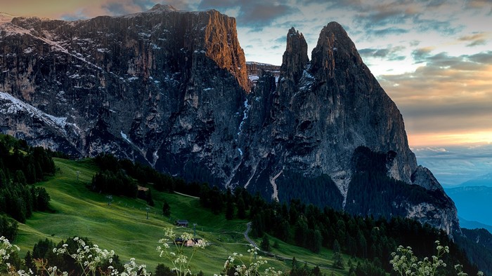 Dolomites mountains at sunset with green meadows