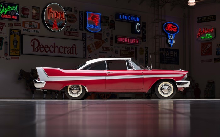 Red and white Plymouth Fury car with vintage signs