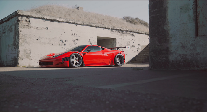 Red Ferrari 458 Italia parked near concrete structure