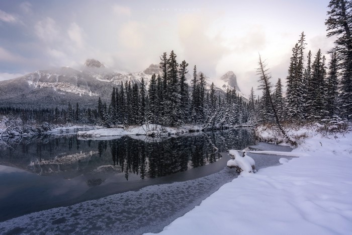 Snowy mountains and forest reflected in a calm winter river