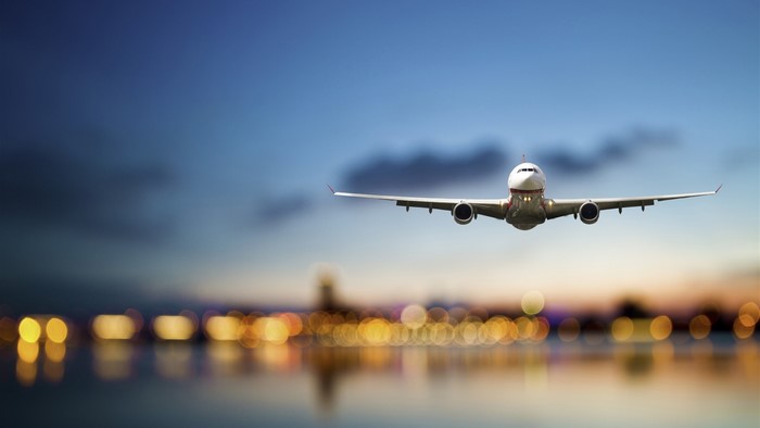 Airplane flying over city lights at dusk