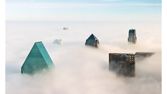 Skyscrapers emerging from thick fog in a city