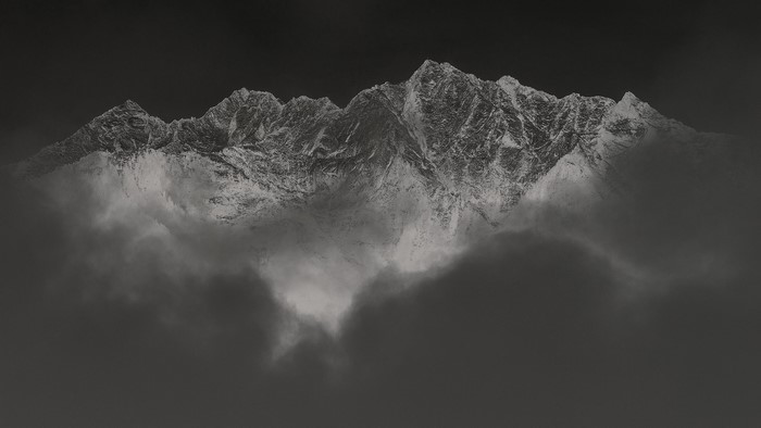 Snow-capped mountains emerging from clouds, monochrome