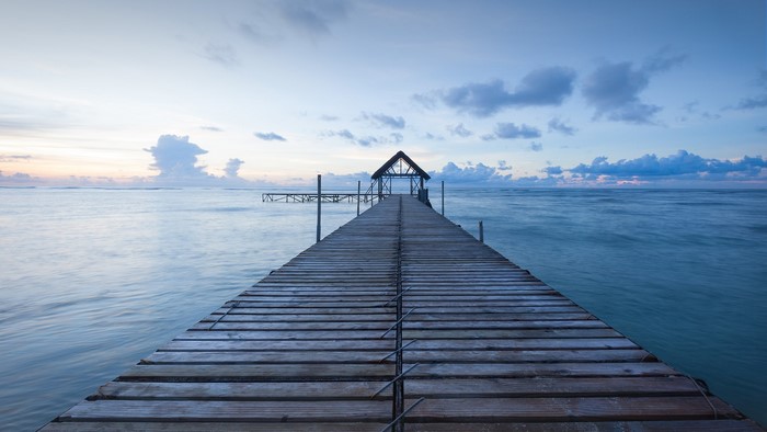 Wooden pier with a shelter over the ocean at sunset