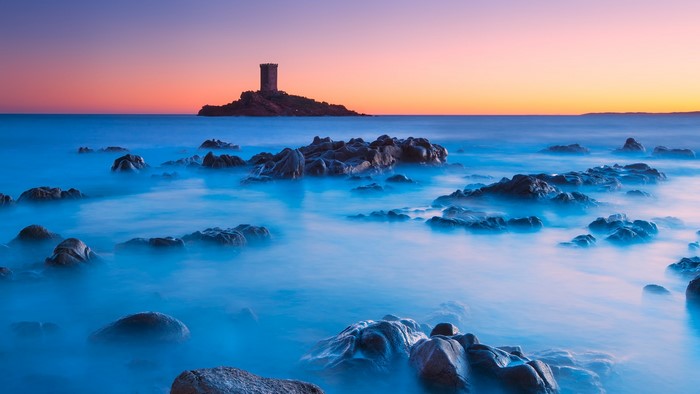Rocky coastline with tower at sunset, long exposure