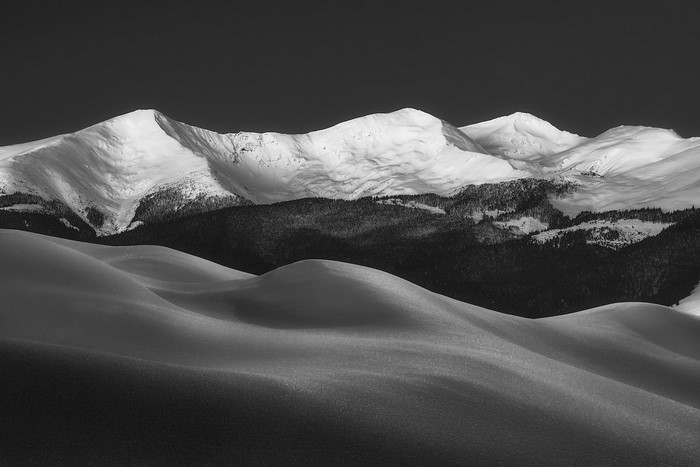 Snow-covered mountains and rolling hills in monochrome