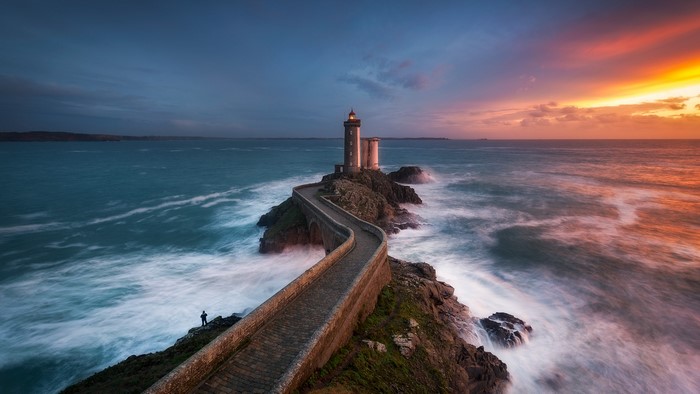 Lighthouse on a rocky island with a long exposure sea at sunset