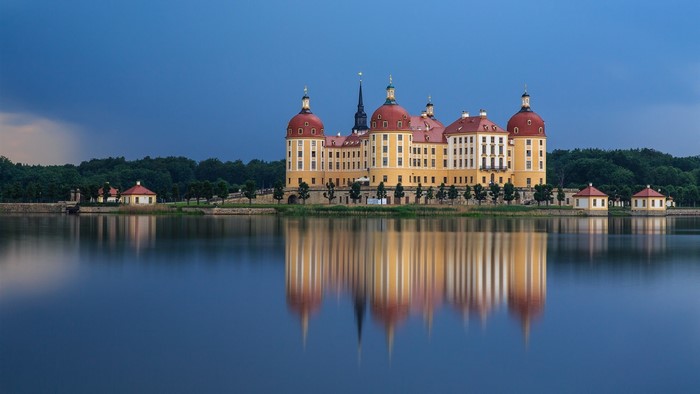 Moritzburg Castle reflected in a lake under a stormy sky