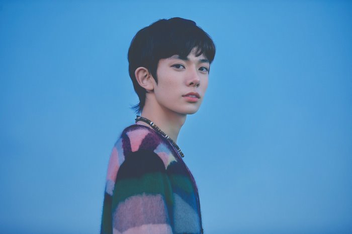 Heeseung from ENHYPEN posing against blue background