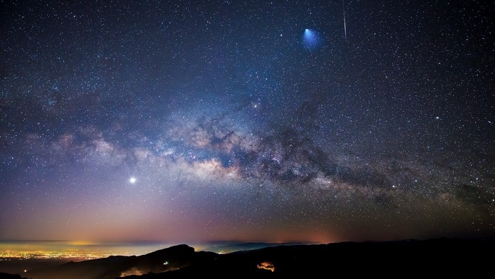 Milky Way and meteor shower over city lights