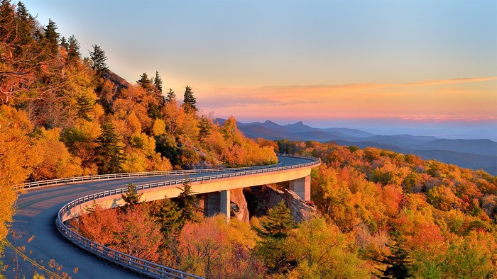 Mountain road with autumn trees at sunset