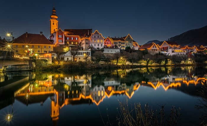 Town with Christmas lights reflected in river at night