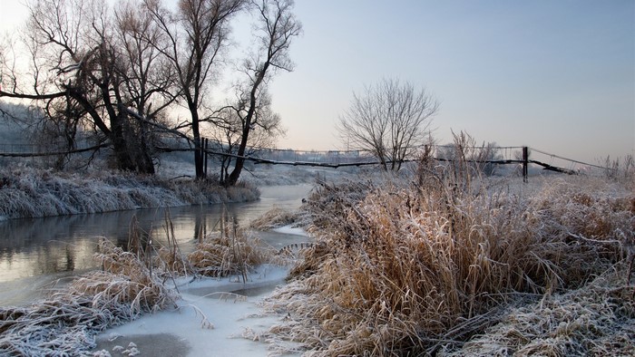 Frozen river and bridge in winter landscape