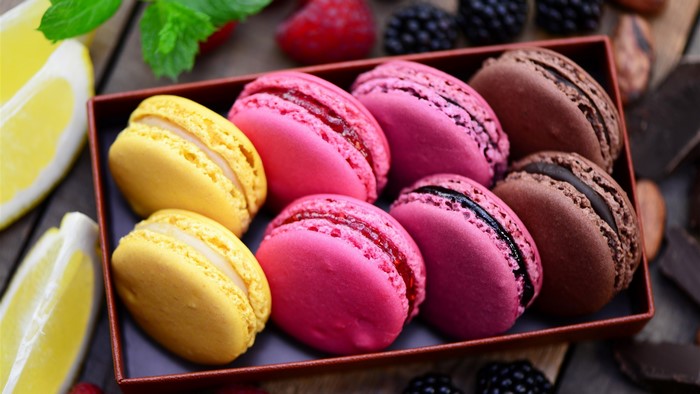 Assortment of colorful macarons with berries and lemon slices